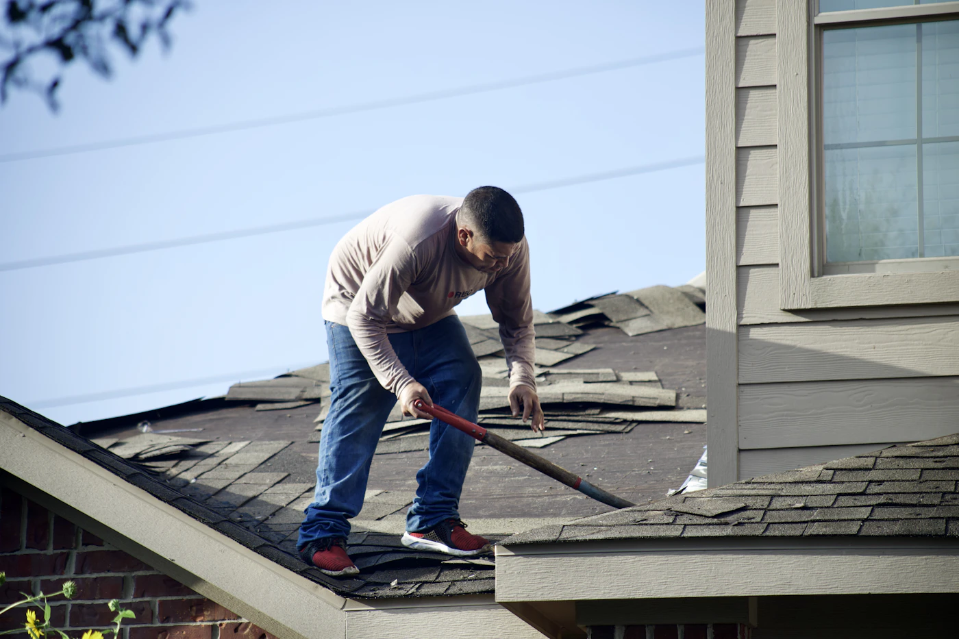 Worker removing old shingles from a residential roof