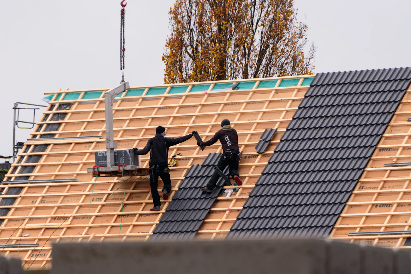 Construction workers installing roof tiles on a building